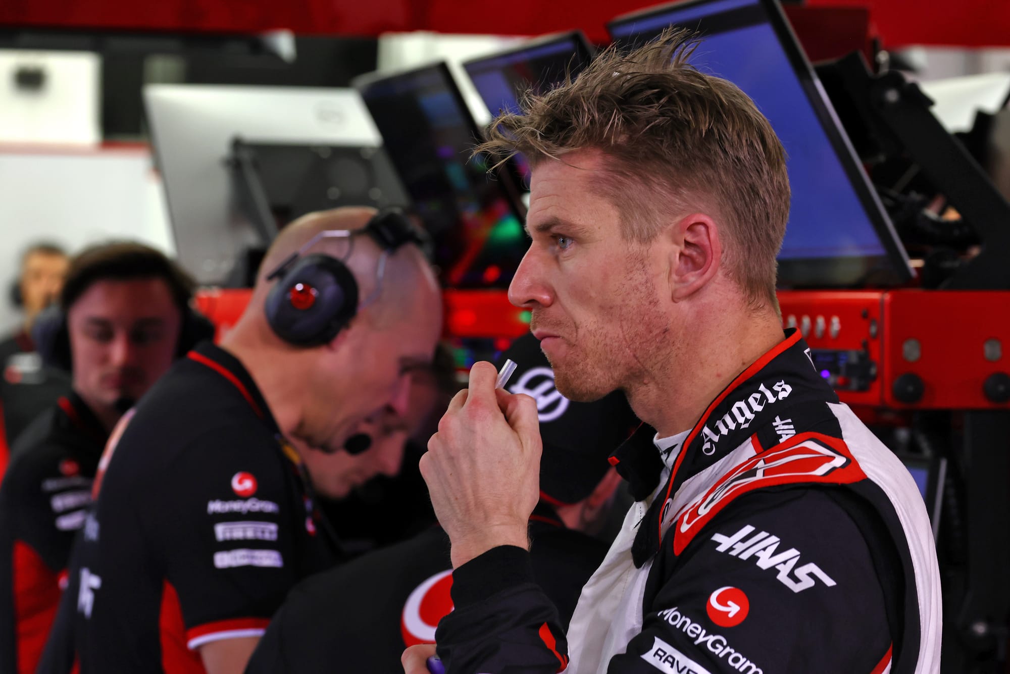 Nico Hulkenberg sips his drink as Haas employees work on computers in Bahrain F1 testing, 2024