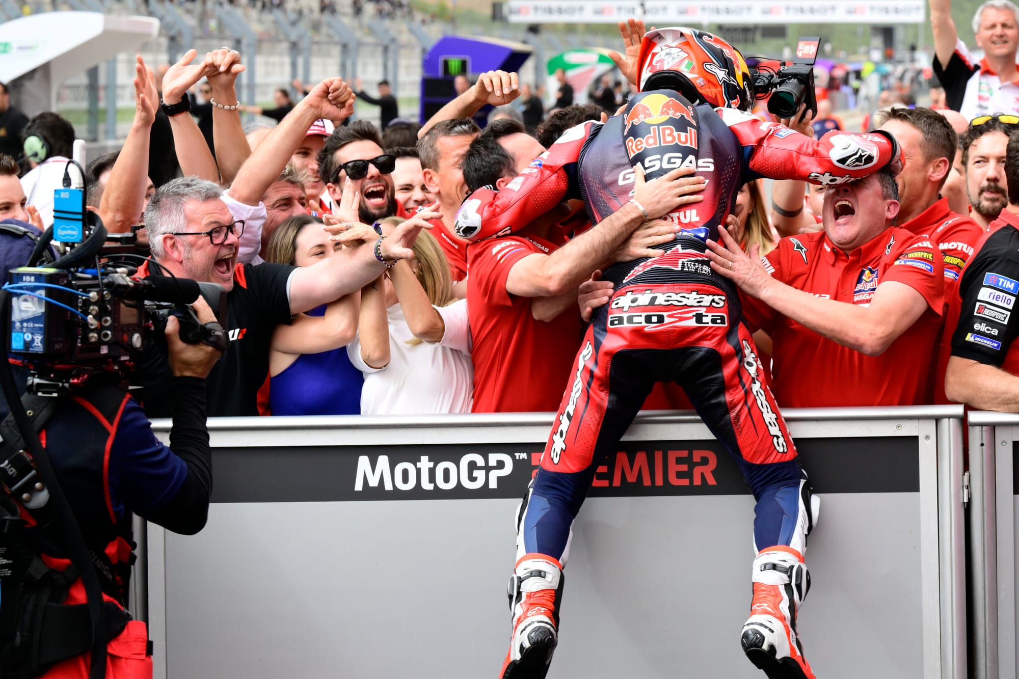 Pedro Acosta jumps over a barrier to celebrate with his team after a MotoGP podium at Portimao, 2024