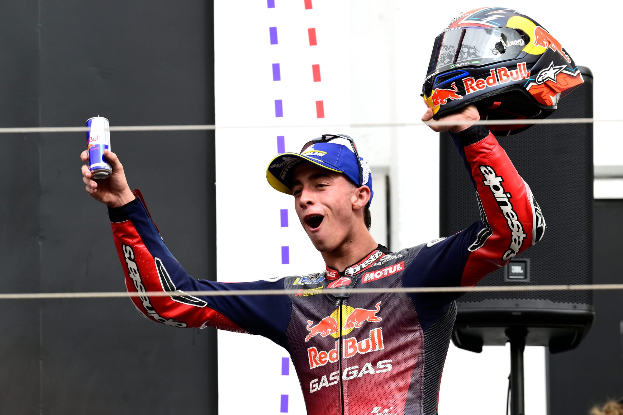 Pedro Acosta raises his helmet and a Red Bull celebrating on the podium, Portimao MotoGP 2024
